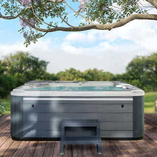 Whirlpool im Garten auf Holzterrasse – modernes Outdoor-Spa mit grauer Verkleidung und Einstiegstreppe unter blühendem Baum